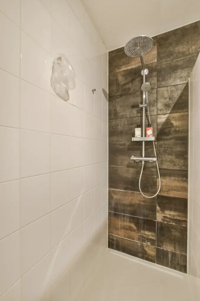 Free standing white bathtub with a tilled wall backdrop.