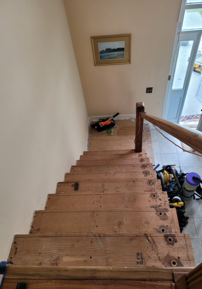 Wooden stairs with handrail under installation in residential home.