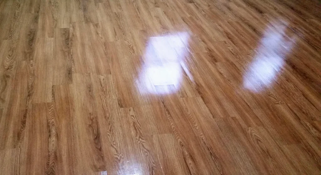A close-up image of hardwood flooring showing signs of wear and tear, including scratches and discoloration. This image illustrates the need for hardwood floor refinishing.