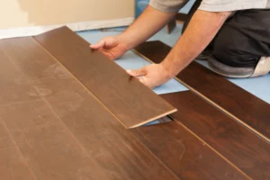 A close-up shot of a professional installer carefully placing a laminate wood flooring plank during installation. The image emphasizes the precision and skill involved in professional laminate flooring installation.