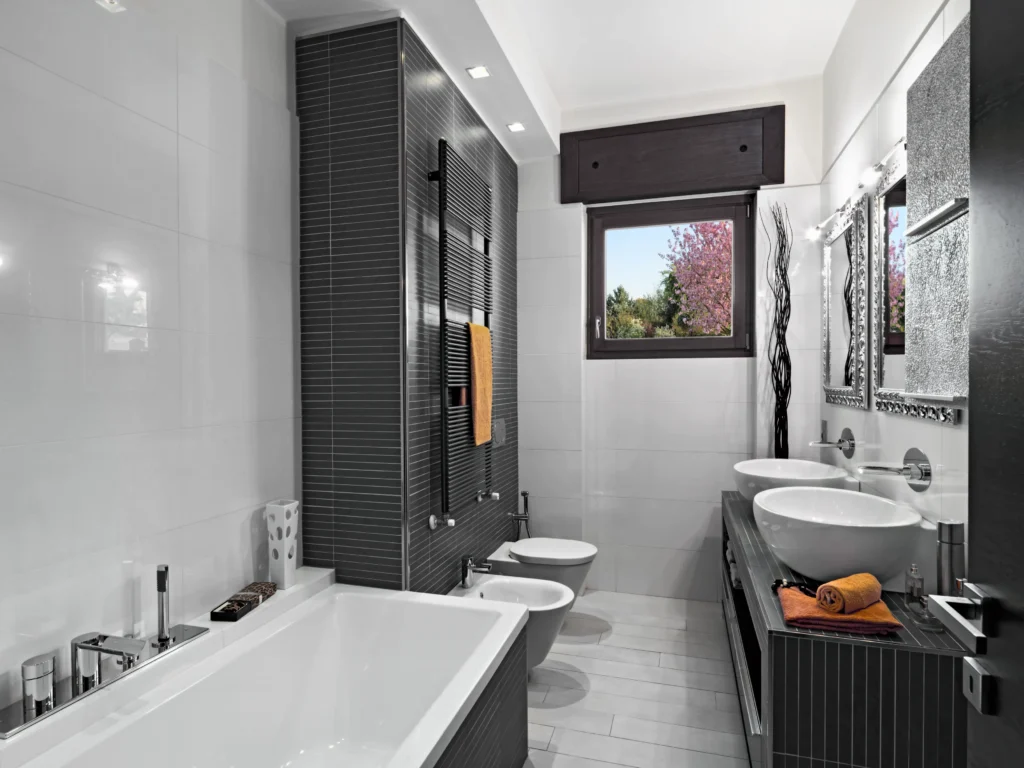 A stylish small bathroom with dark gray and white tile, a modern bathtub, and double vanity. This image showcases design elements for a successful small bathroom remodel.