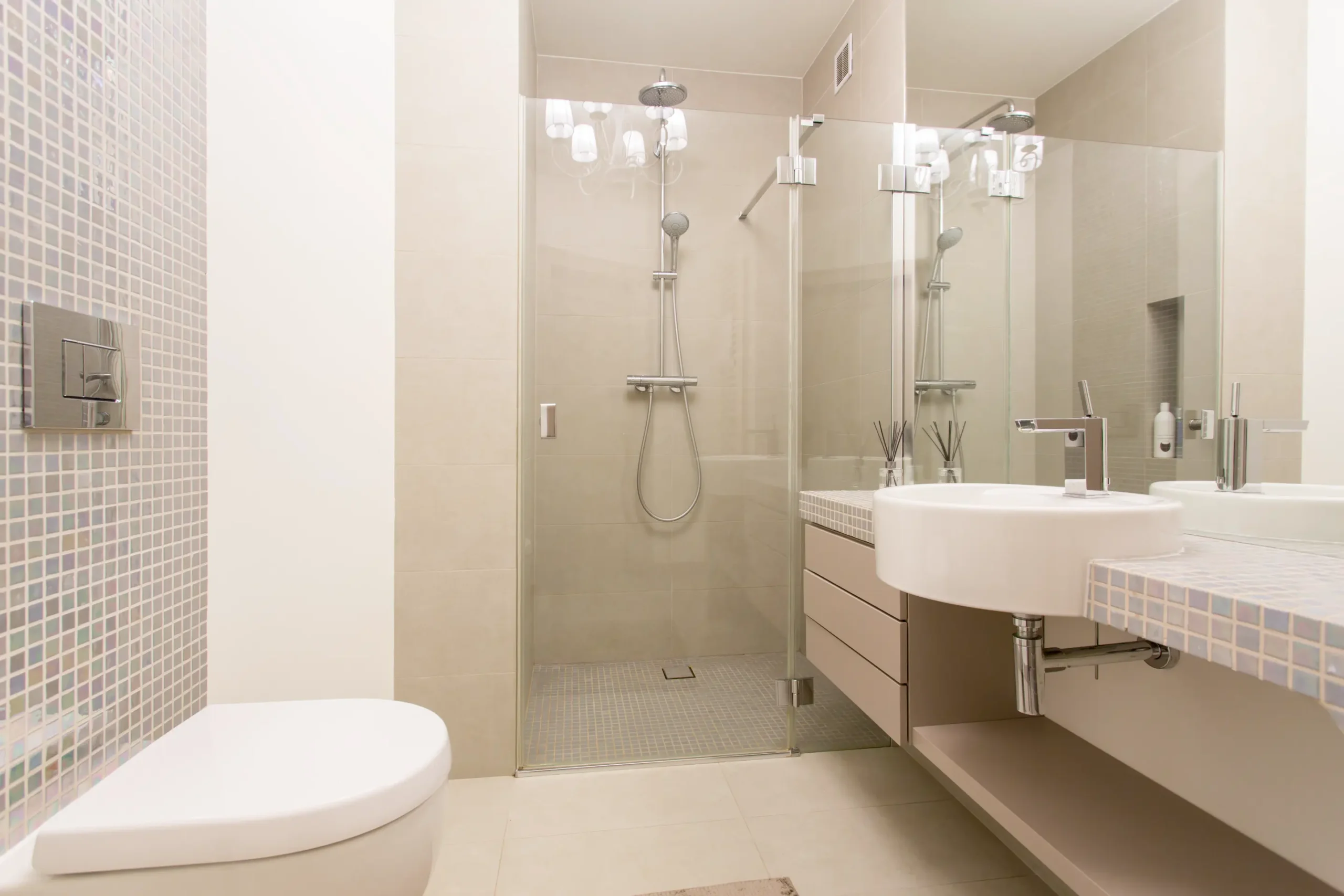 A modern, small bathroom with a large walk-in shower, showcasing a space-saving design achieved by converting a bathtub to a shower. The bathroom features a contemporary vanity and mosaic tile accents.