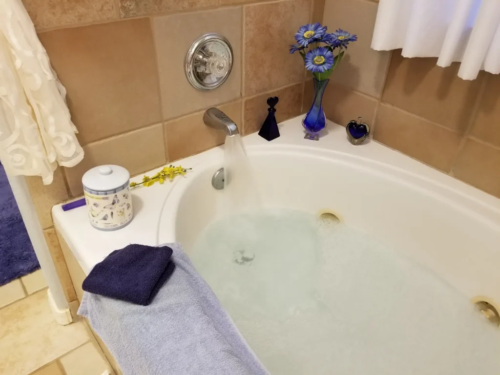 A walk-in bathtub in a bathroom setting. The tub is partially filled with water, and there are bath accessories such as towels and toiletries visible nearby. The overall impression is one of comfort and accessibility.