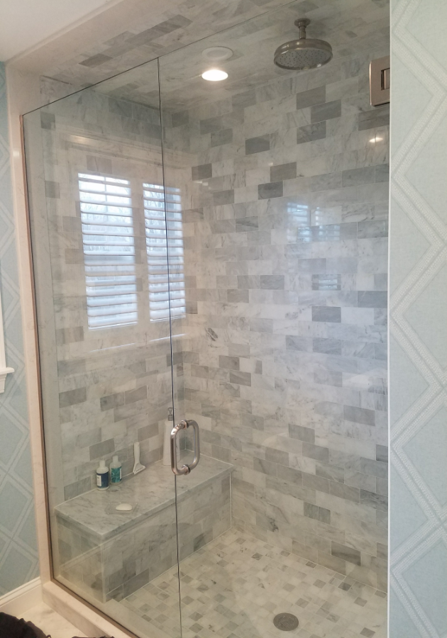 Contemporary bathroom renovation with glass shower with a tiles wall backdrop.